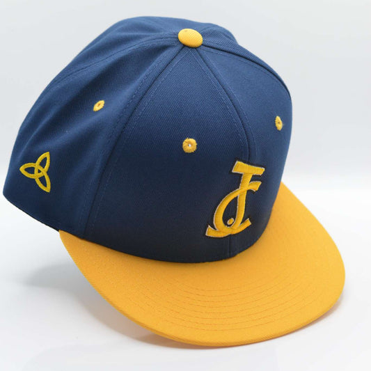 Bold faith, royal style. The JC Snapback in navy and gold represents divine authority and chosen identity. A signature release from Aaron David Apparel.


