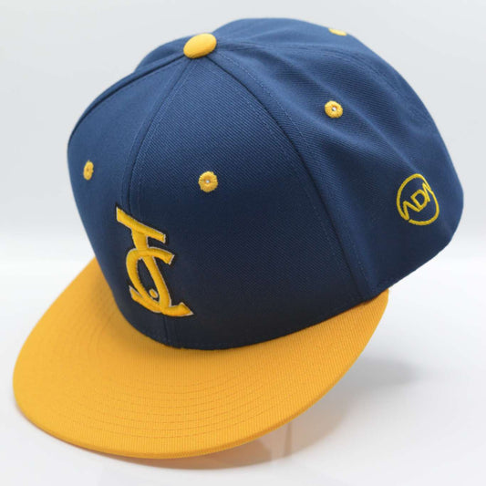 Bold faith, royal style. The JC Snapback in navy and gold represents divine authority and chosen identity. A signature release from Aaron David Apparel.

